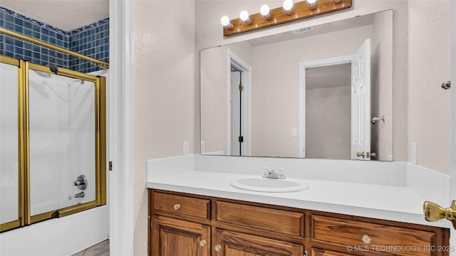 bathroom with vanity and shower / bath combination with glass door