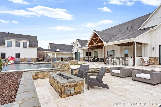 view of patio / terrace with an outdoor living space with a fire pit, pool water feature, ceiling fan, and exterior bar