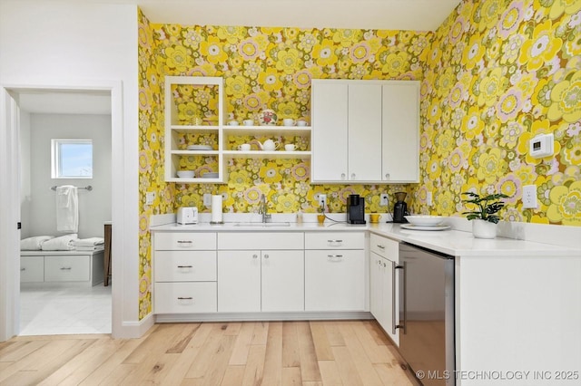 kitchen with white cabinetry, sink, fridge, and light wood-type flooring