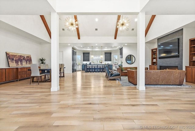 living room with a notable chandelier, light hardwood / wood-style flooring, and high vaulted ceiling