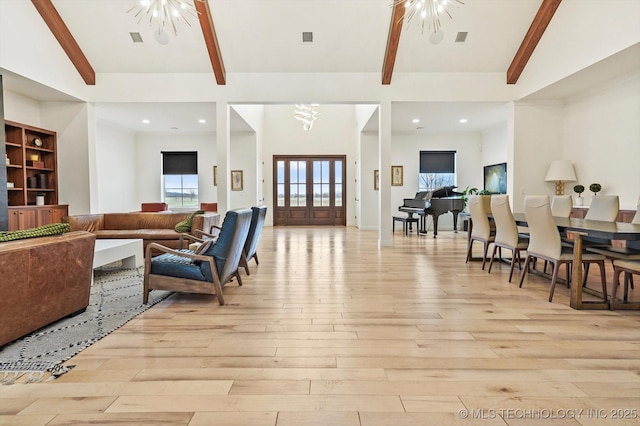 living room with an inviting chandelier, beam ceiling, light hardwood / wood-style floors, and a high ceiling