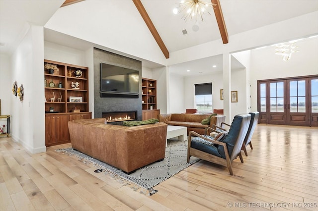 living room featuring high vaulted ceiling, a chandelier, and light hardwood / wood-style floors