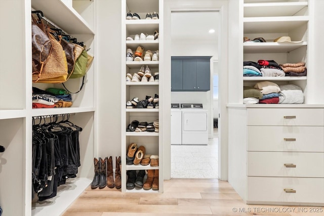 spacious closet featuring washer and clothes dryer and light hardwood / wood-style floors