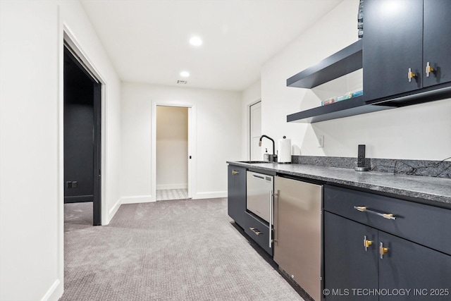 kitchen featuring sink, light carpet, and refrigerator