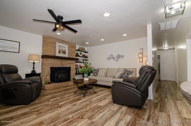 living room with ceiling fan, a fireplace, and light wood-type flooring