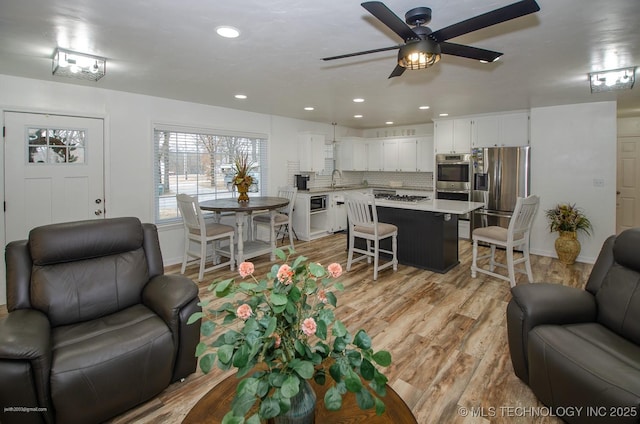 living room with ceiling fan and light wood-type flooring