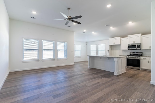 kitchen with stainless steel appliances, a kitchen island with sink, a sink, and white cabinetry