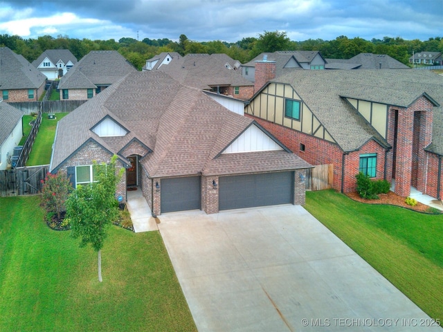 view of front of home featuring an attached garage, brick siding, fence, roof with shingles, and a front lawn