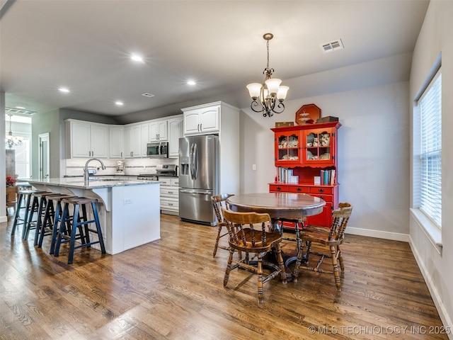 kitchen with white cabinetry, an inviting chandelier, decorative light fixtures, appliances with stainless steel finishes, and dark stone counters