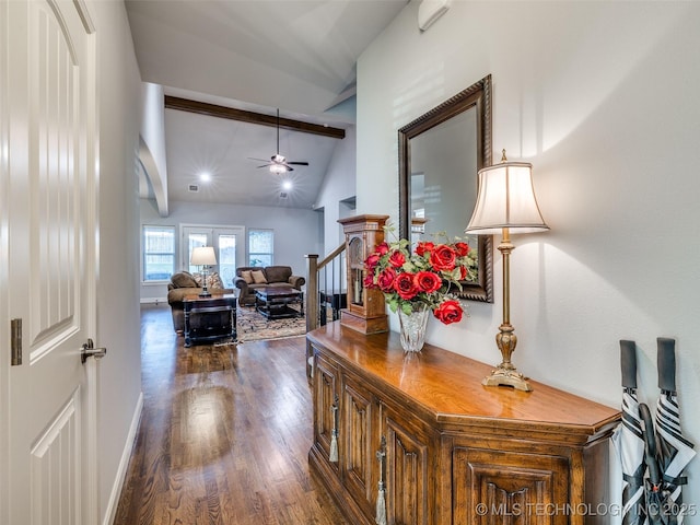 hall featuring dark wood-style floors, stairs, baseboards, and vaulted ceiling