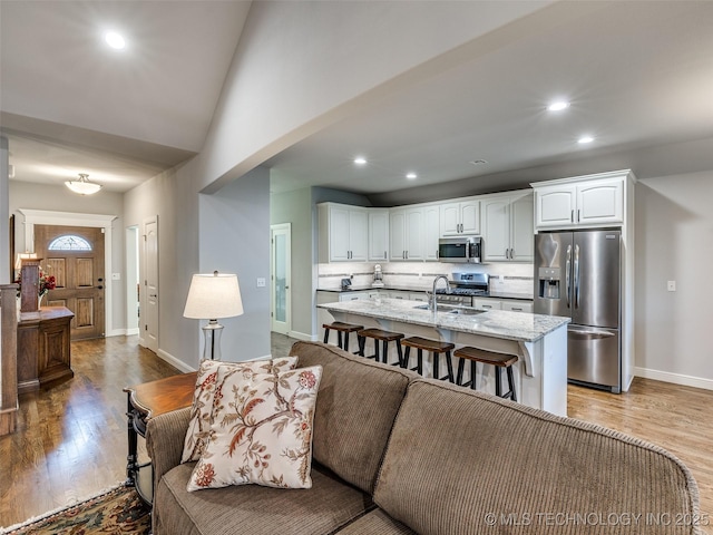 living room with light wood-type flooring, baseboards, vaulted ceiling, and recessed lighting