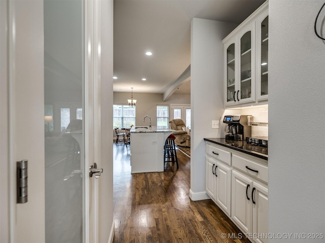 kitchen with white cabinetry, dark wood-type flooring, pendant lighting, and a kitchen bar