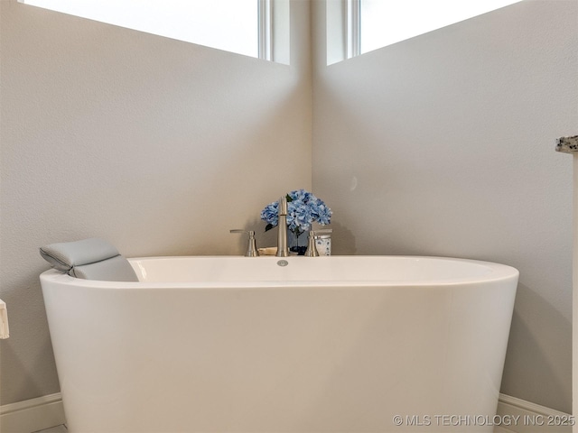 bathroom with a freestanding bath and baseboards