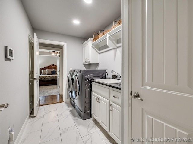 clothes washing area with cabinets, sink, and washing machine and clothes dryer