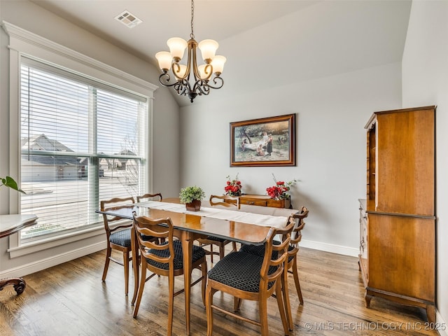 dining room featuring a chandelier, light wood-type flooring, visible vents, and baseboards