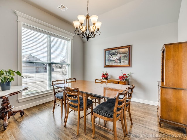 dining space featuring baseboards, an inviting chandelier, visible vents, and light wood-style floors