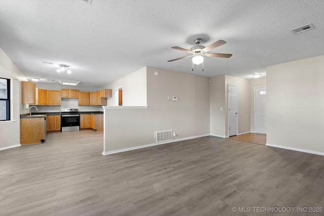 unfurnished living room with ceiling fan, sink, a textured ceiling, and light wood-type flooring