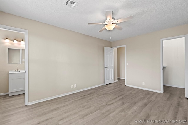 unfurnished bedroom with sink, light hardwood / wood-style flooring, and a textured ceiling