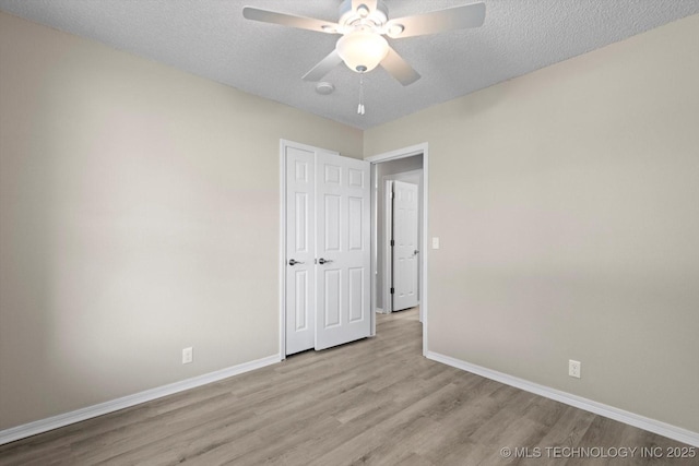 unfurnished room featuring ceiling fan, a textured ceiling, and light wood-type flooring