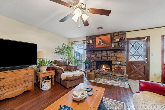 living room featuring hardwood / wood-style flooring, a stone fireplace, and ceiling fan