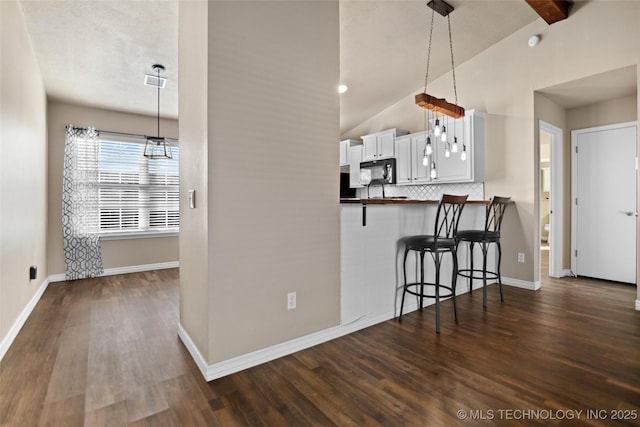 kitchen with white cabinetry, dark wood-type flooring, pendant lighting, and a kitchen bar