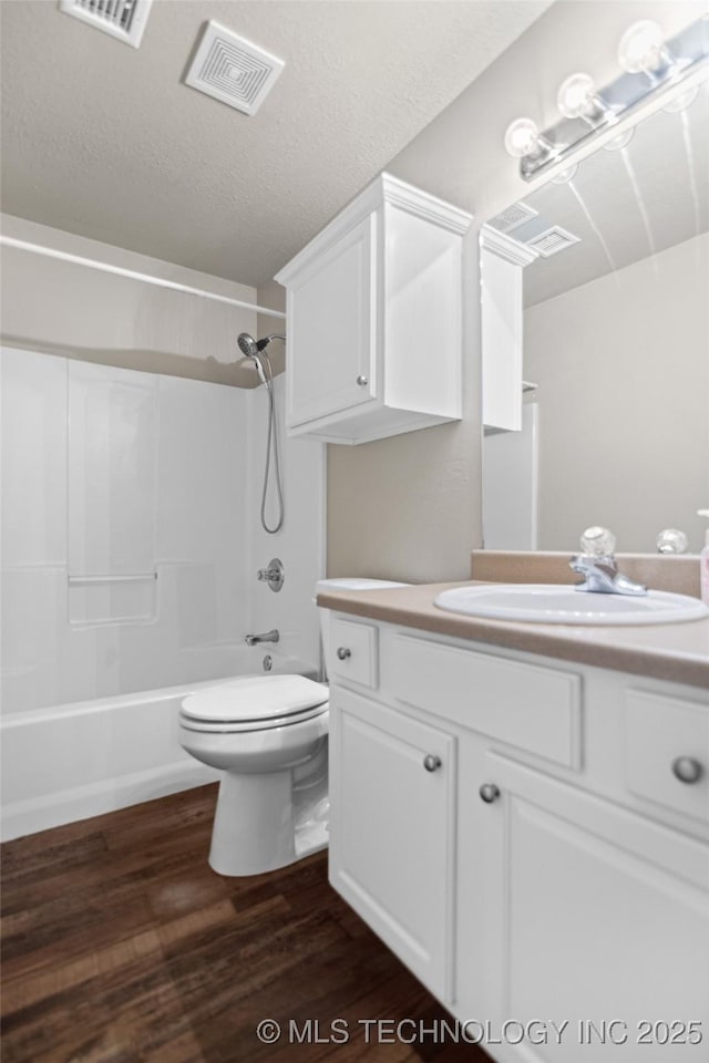 full bathroom with toilet, a textured ceiling, vanity, hardwood / wood-style flooring, and shower / bath combination