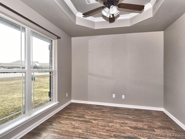 empty room with dark hardwood / wood-style flooring, a tray ceiling, and ceiling fan