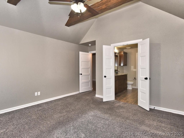 unfurnished bedroom featuring ensuite bath, vaulted ceiling, and dark colored carpet