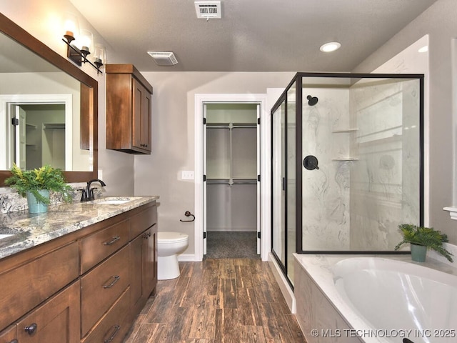 full bathroom with vanity, wood-type flooring, shower with separate bathtub, and toilet