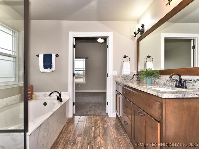 bathroom with vanity, a tub, and wood-type flooring