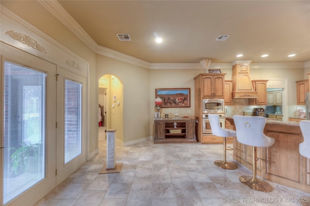 kitchen featuring crown molding, appliances with stainless steel finishes, a kitchen breakfast bar, and custom range hood