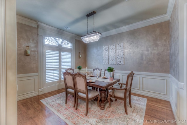 dining area with ornamental molding, light hardwood / wood-style floors, and a chandelier