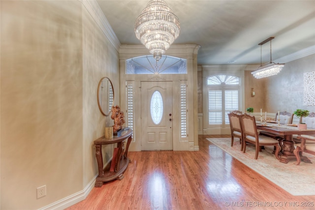 foyer with crown molding, light hardwood / wood-style floors, and a notable chandelier