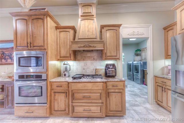 kitchen with stainless steel appliances, light stone counters, ornamental molding, washer and dryer, and decorative backsplash