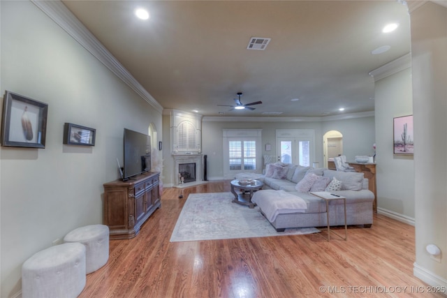 living room with ceiling fan, ornamental molding, and light hardwood / wood-style flooring