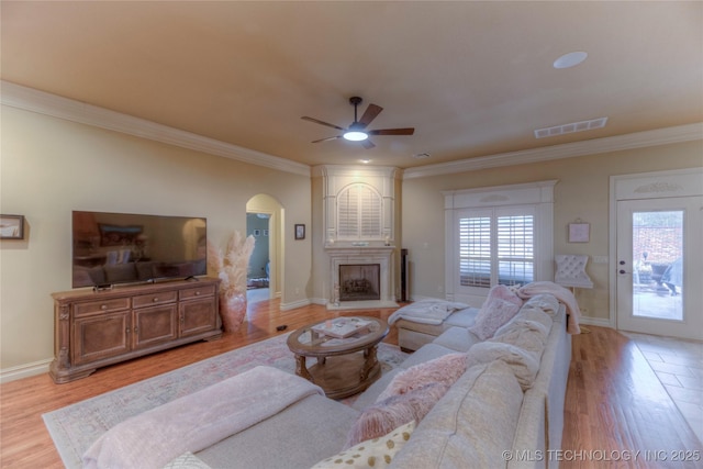 living room with a large fireplace, ornamental molding, and light hardwood / wood-style flooring