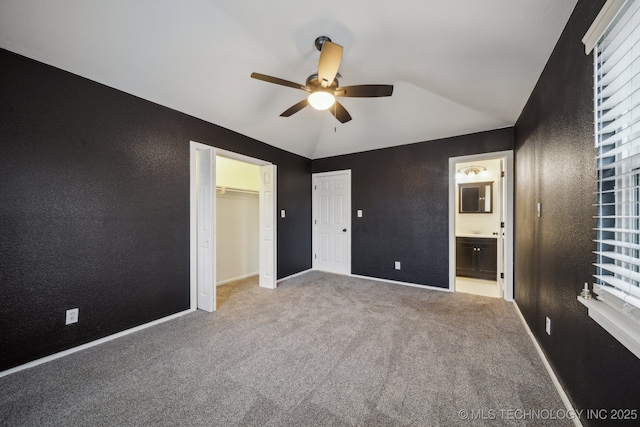 unfurnished bedroom with lofted ceiling, light carpet, connected bathroom, and ceiling fan