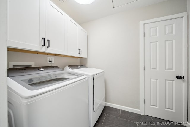 clothes washing area featuring cabinets, dark tile patterned flooring, and washing machine and clothes dryer