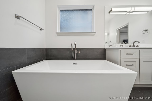 bathroom featuring vanity, a bathing tub, tile patterned flooring, and tile walls