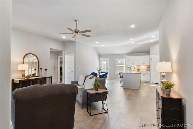 living room with vaulted ceiling, ceiling fan, sink, and light hardwood / wood-style flooring