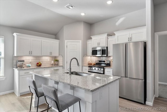 kitchen with a kitchen island with sink, sink, stainless steel appliances, and white cabinets