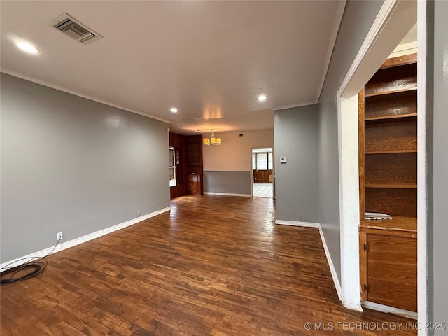 spare room with crown molding, dark hardwood / wood-style floors, and an inviting chandelier