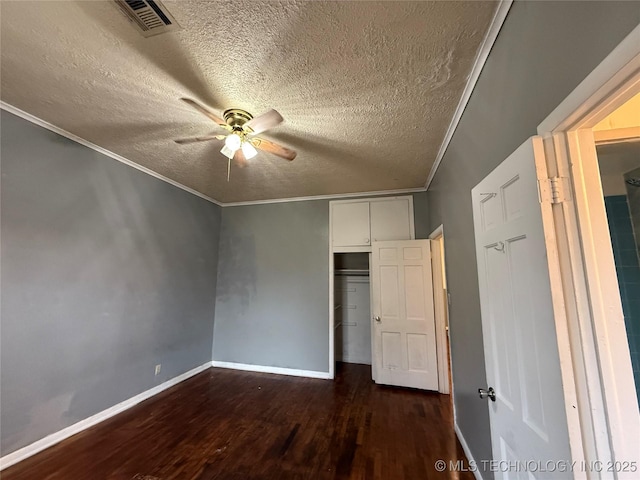 unfurnished bedroom with dark hardwood / wood-style flooring, ornamental molding, ceiling fan, a textured ceiling, and a closet