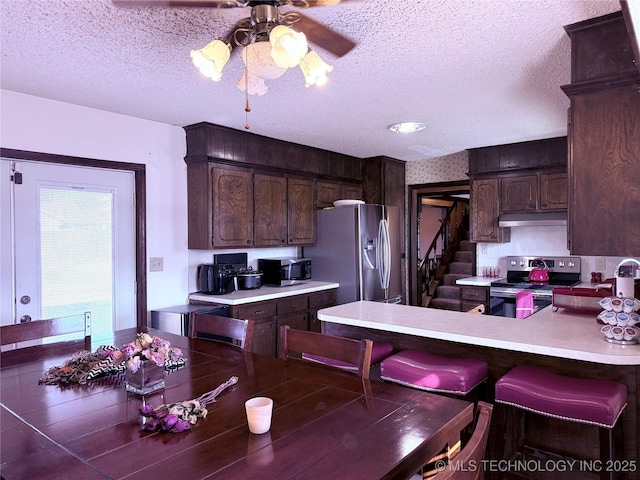 kitchen featuring dark brown cabinets, stainless steel appliances, kitchen peninsula, and a textured ceiling