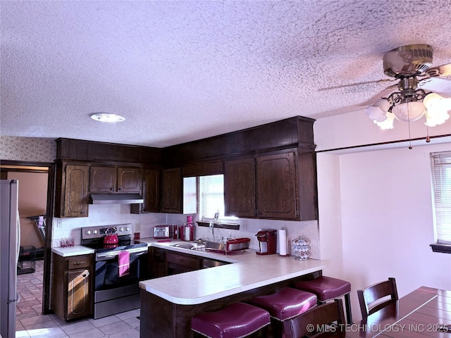 kitchen featuring sink, a textured ceiling, a kitchen breakfast bar, kitchen peninsula, and stainless steel appliances