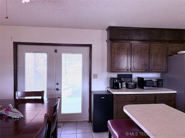 kitchen with dark brown cabinets, fridge, plenty of natural light, a textured ceiling, and french doors