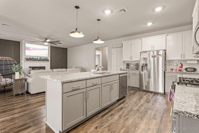 kitchen with stainless steel appliances, dark hardwood / wood-style floors, an island with sink, and hanging light fixtures