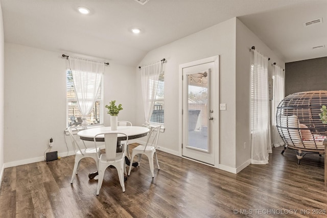 dining room with dark wood-type flooring and vaulted ceiling