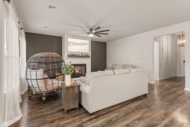 living room featuring dark wood-type flooring, ceiling fan with notable chandelier, and a wealth of natural light