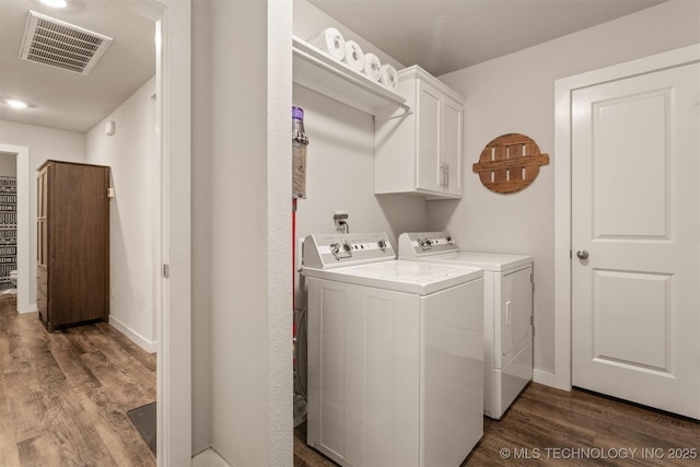 washroom with separate washer and dryer, dark hardwood / wood-style floors, and cabinets